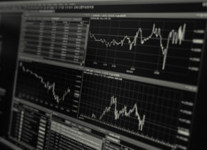 Texto em alusão a um gráfico de linhas na tela de um operador de bolsa que utiliza ferramentas de Factor investing no seu processo de investimento.